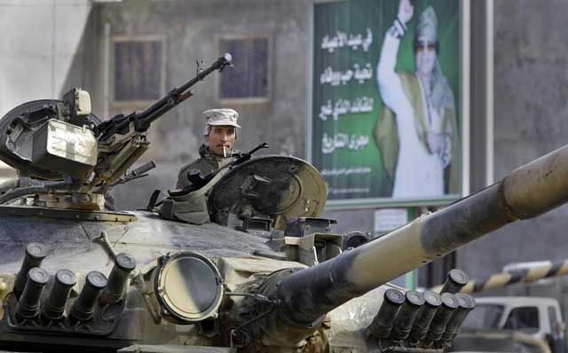 Un soldado del ejrcito leal a Gadafi, junto a un cartel del coronel libio. | Ap