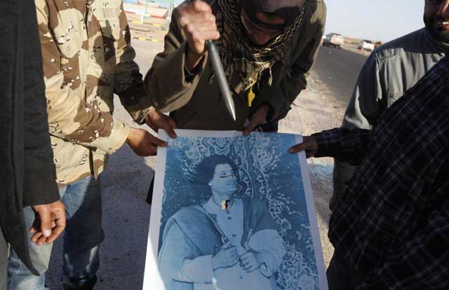Un rebelde apuala una imagen del coronel libio Muamar Gadafi. | Reuters