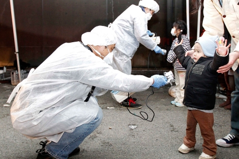 Un operario mide la posible radiación en los niños de la zona. | Reuters