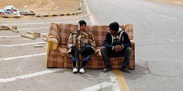 Rebeldes libios descansan en un silln en un puesto de vigilancia en Ajdabiya. | Reuters