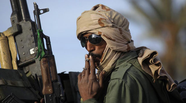 Un soldado pro Gadafi fuma un cigarrillo a la espera de seguir los combates. | Ap