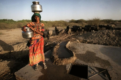 Una mujer recoge agua de un pozo provisional en India.| Ap