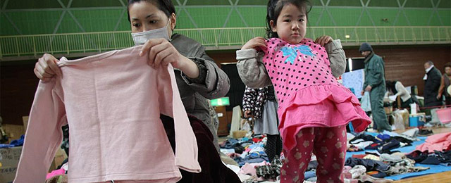 Una mujer y su hija buscan ropa de segunda mano en un centro. | AFP