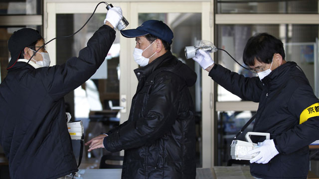 Dos agentes miden la radiacin de un ciudadano en Fukushima. | Reuters