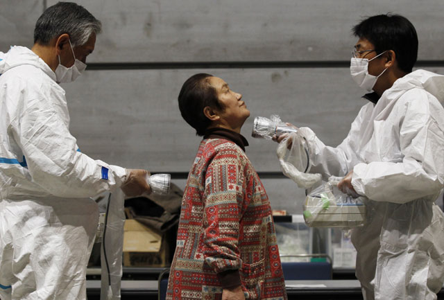 Dos hombres realizan un control de radiacin a una mujer en Japn. | Reuters