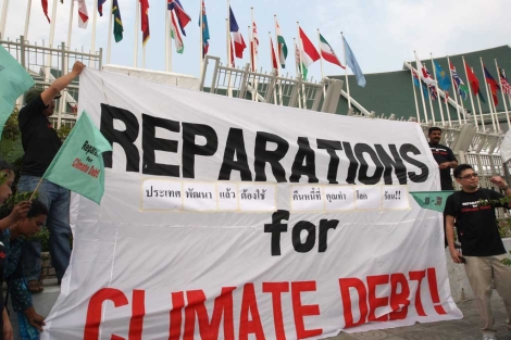 Manifestantes con una pancarta con el lema 'Reparaciones por la deuda climtica'. | Efe.