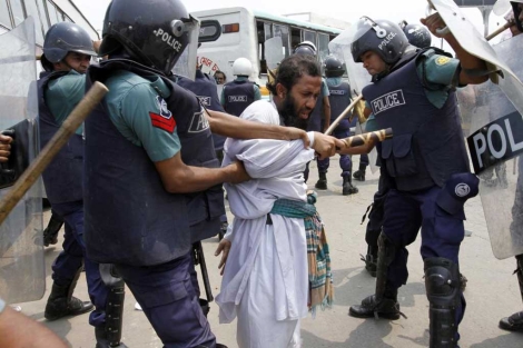 La polica golpea a un manifestante en las protestas en Dhaka. | Reuters