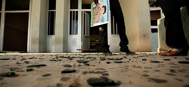Un estudiante con un retrato de Gadafi ante los destrozos supuestamente causados en la Universidad Al Fatah. | Reuters