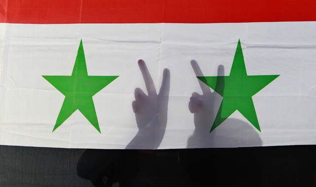 Gestos de victoria ante una bandera siria. | Reuters