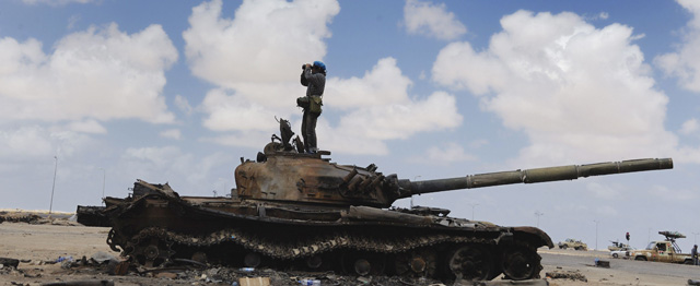 Un rebelde libio sobre un tanque destrozado de los leales a Gadafi. | Efe