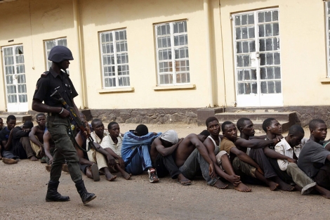 Un polica nigeriano vigila a los supuestos autores de unos disturbios en Kaduna. | AP