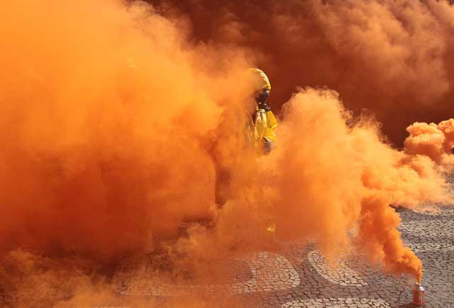 Un activista de Greenpeace envuelto en humo naranja. | Efe.
