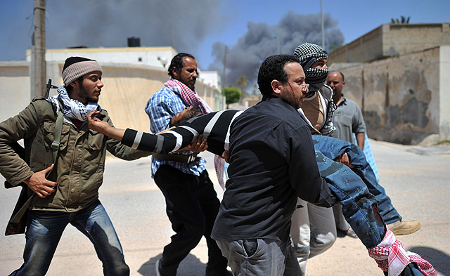 Rebeldes libios trasladan a un compañero herido en Misrata. | AFP