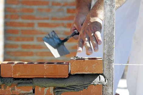 Un obrero extiende cemento para colocar ladrillos|Ical