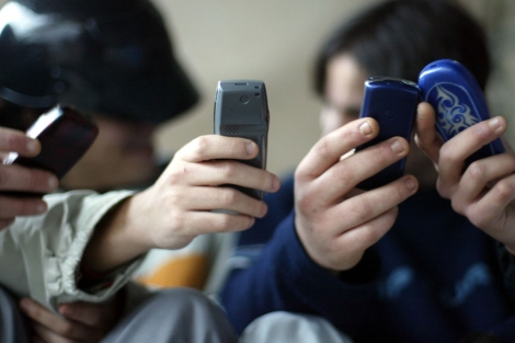 Unos chavales envian mensajes cortos con sus telfonos mviles.| Pablo Quiza