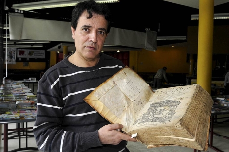 El profesor Juan Antonio Rgil con el libro de Santo Toms de Aquino rescatado. | J. C. | Efe