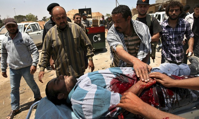 Rebeldes libios ayudan a un compaero herido en combate contra las tropas leales a Gadafi. | Efe