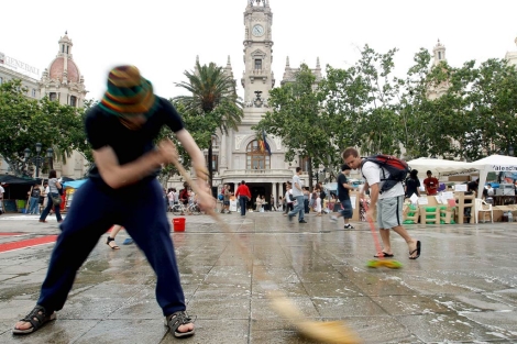 Varios jvenes limpian la plaza del Ayuntamiento de Valencia. | Efe