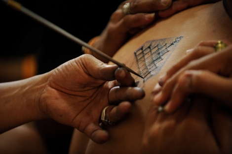 Un artista dibujando un tatuaje tradicional en Bangkok. | Afp