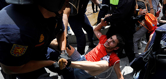 Agentes antidisturbios desalojan a un indignado ante la Casa de la Villa. | AFP