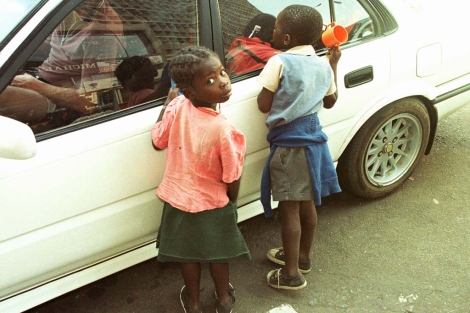 Nios piden limosna a un conductor en Harare.| AP