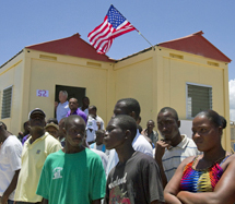 Varios haitianos delante de una de las casas presentadas. | Ap