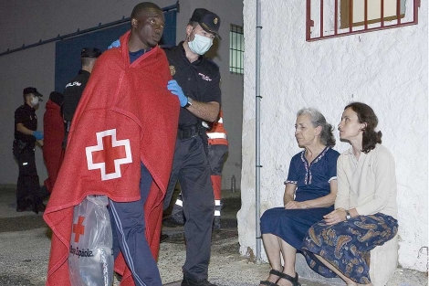 Un inmigrante, escoltado, tras ser atendido por la Cruz Roja. | Efe