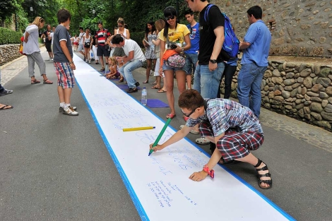 Un grupo de turistas, junto a la Alhambra, participa en el 'Poema gigante'. | Jess G. Hinchado