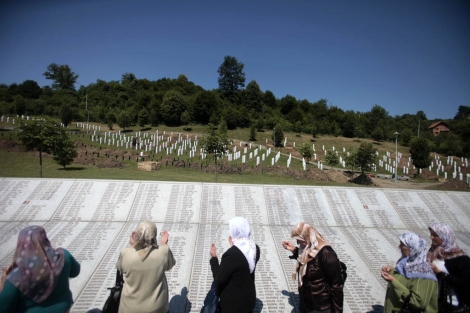 Varias mujeres rezan cerca de las tumbas en memoria de los cados en Srebrenica. | Reuters