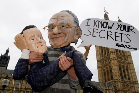 Un hombre disfrazado de Murdoch y Cameron protesta ante el parlamento británico. | AP