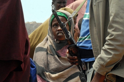 Una joven somal espera su racin de comida junto a un militar.| Afp