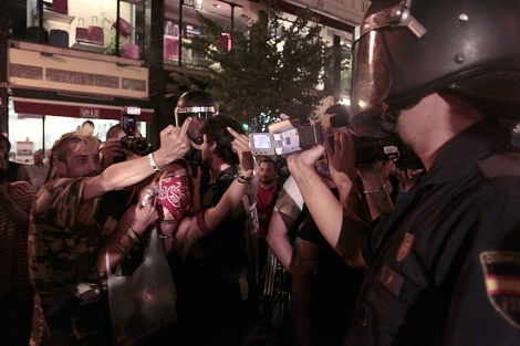 Dos manifestantes hacen un gesto a un polica que les graba. | Antonio Heredia