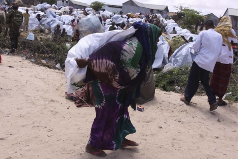 Una mujer somal carga comida y utensilios donados por ACNUR en Mogadiscio.| AP