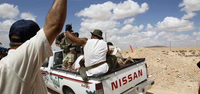 Rebeldes libios transportan a un grupo de gadafistas apresados a las afueras de Bani Walid. | Reuters