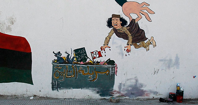 Gadafi, arrojado a un contenedor en el que pone 'Basura de la Historia', en una pintada en Trpoli. | AP