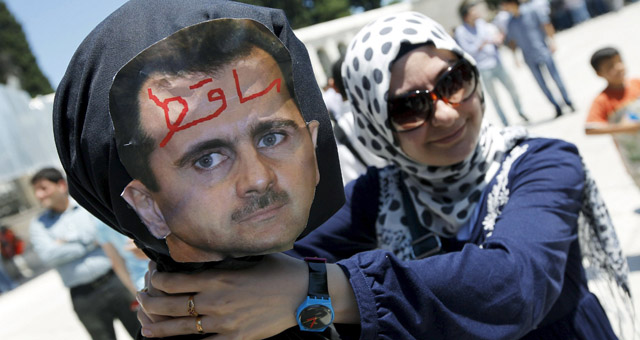 Una manifestante siria en Estambul estrangula un muñeco con la cara de Bashar Asad. | Reuters
