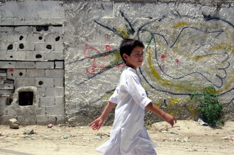 Un nio palestino pasa ante un muro con la paloma de la paz pintada. | AP