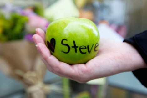 Una mujer sostiene una manzana con una dedicatoria a Steve Jobs, en California. | Reuters