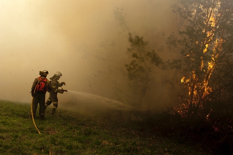 Dos bomberos tratan de sofocar las llamas en Paradella. | Efe