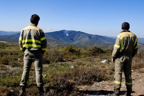 Dos brigadistas observan la tierra calcinada en Vilario de Conso. | Efe