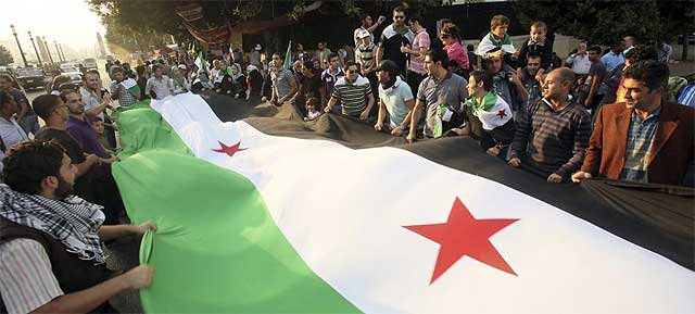 Sirios residentes en Egipto sujetan una gran bandera de Siria