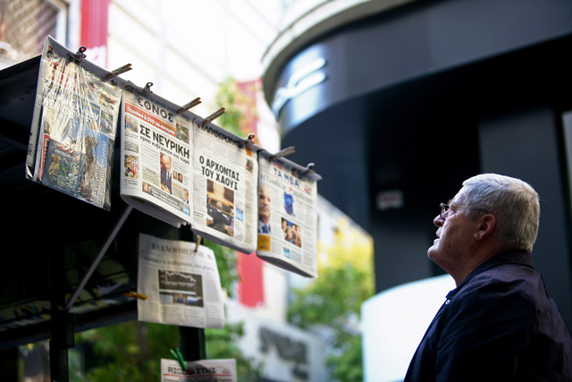 Un peatón lee los periódicos en un quiosco de Atenas. | Efe