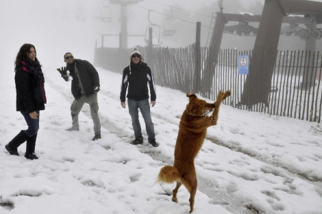 Un grupo de visitantes juega con la nieve. | Efe