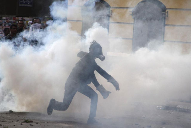 Un joven corre entre el humo de gas lacrimógeno en El Cairo. | EPA VEA MÁS IMÁGENES