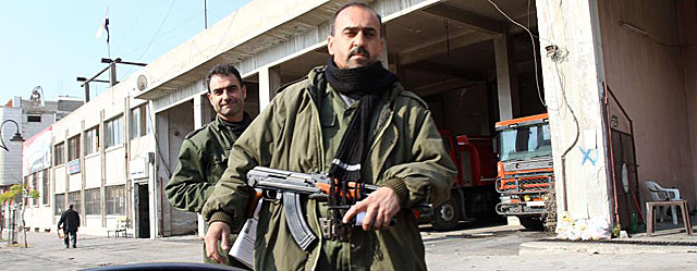 Miembros de las fuerzas de seguridad siria montan guardia en una calle de Homs. | Afp