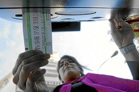 Una joven saca el ticket de aparcamiento en un parqumetro de Madrid. | EM