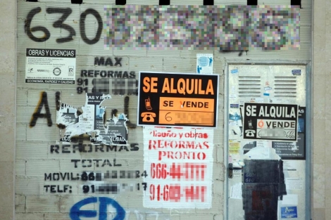 Un bajo de un edificio de pisos plagado de anuncios inmobiliarios. | Diego Sinova
