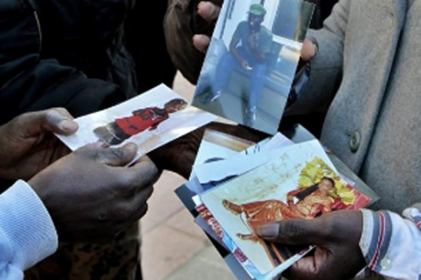 Un grupo de senegaleses muestran fotos de su compatriota asesinado. |Efe