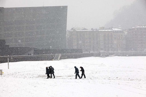 Unas personas pasean por la nevada playa donostiarra de la Concha. | Jon Corostola