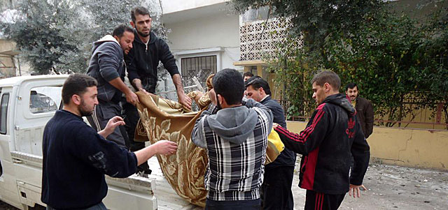 Varios hombres transportan un cadáver en el barrio de Bab Amro, en Homs (Siria). | Afp
